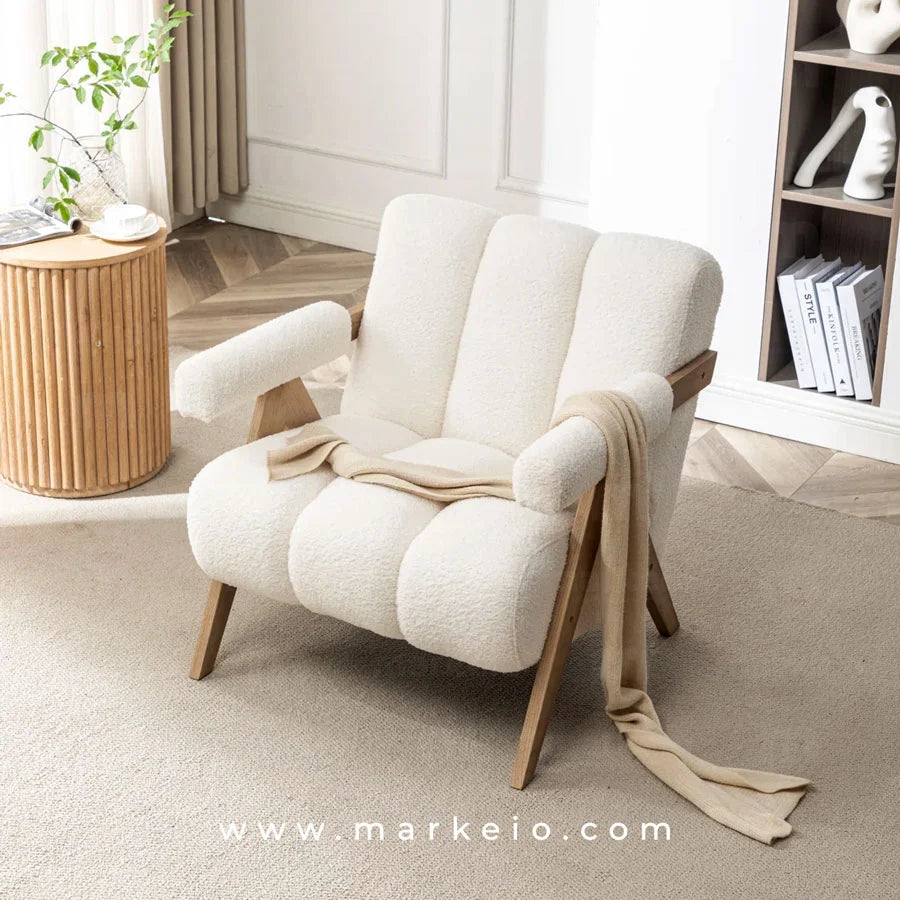Fauteuil Armo en bouclette blanche avec cadre en bois clair dans une pièce minimaliste.