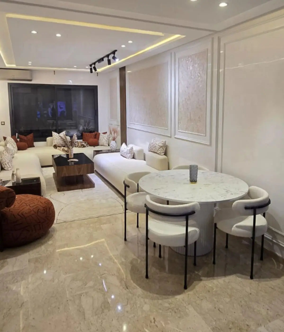 Salle à manger blanche avec finitions en bois de noyer dans un intérieur lumineux à Casablanca.