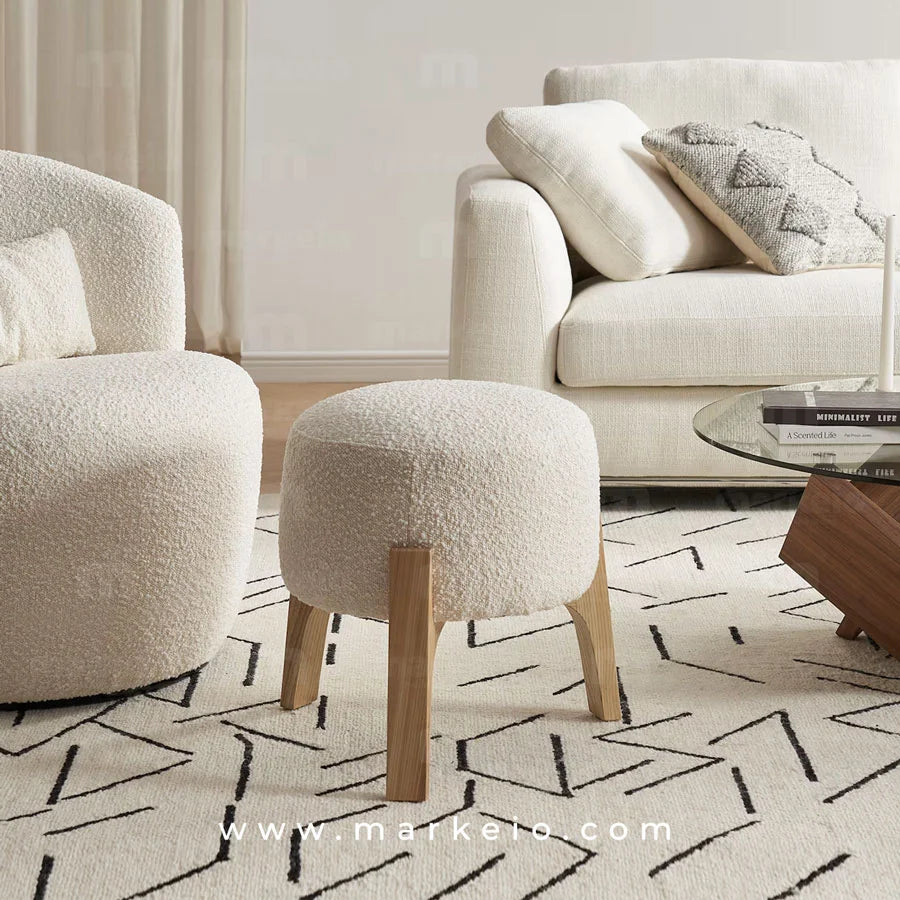 Pouf scandinave blanc installé sur un tapis graphique dans un salon.