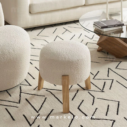 Pouf Snow de Markeio en tissu bouclette blanc avec pieds en bois clair.