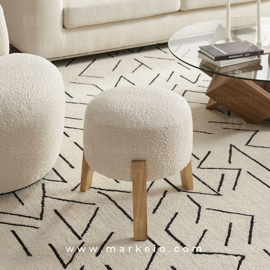 Pouf Snow de Markeio en tissu bouclette blanc avec pieds en bois clair.